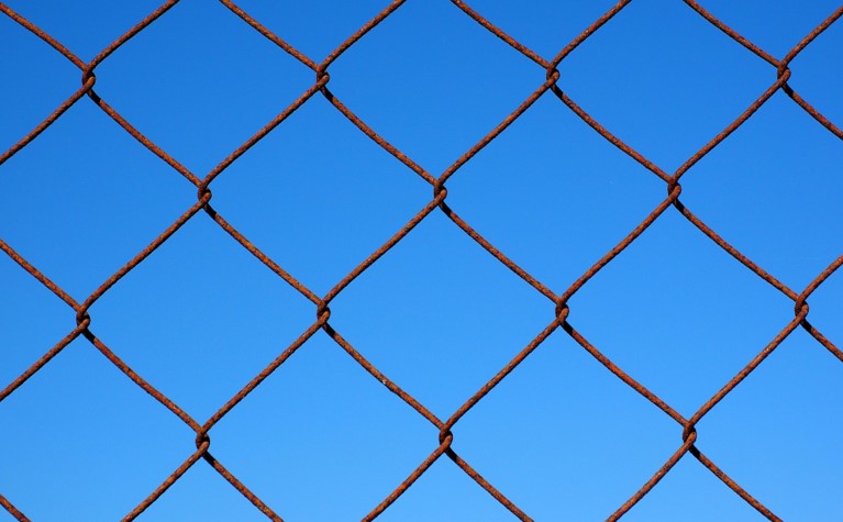 Metal chain link fence against a blue sky background